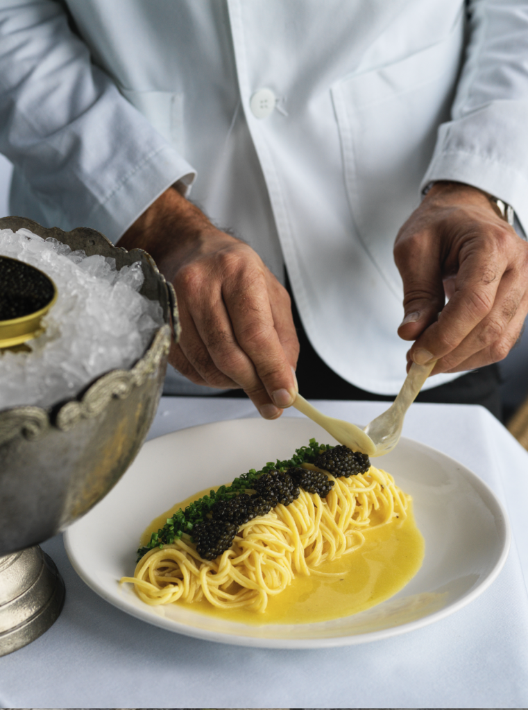 Hands plating a spaghetti dish